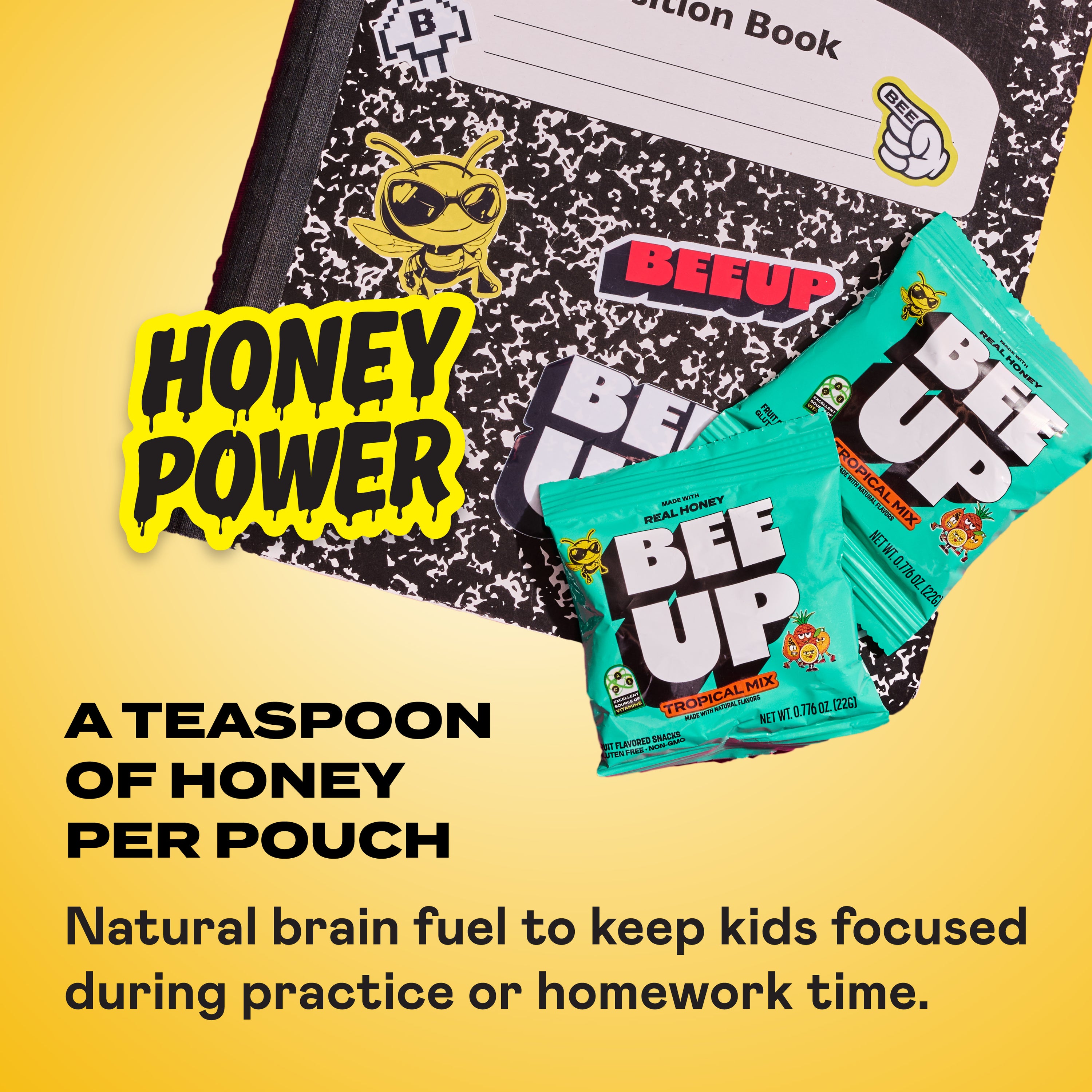 A notebook with BEEUP stickers on a yellow background with two Tropical Mix honey fruit snack pouches stacked on it. There is a large sticker overlay saying "Honey Power"
Text on the bottom says, "A teaspoon of honey per pouch. Natural brain fuel to keep kids focused during practice or homework time."